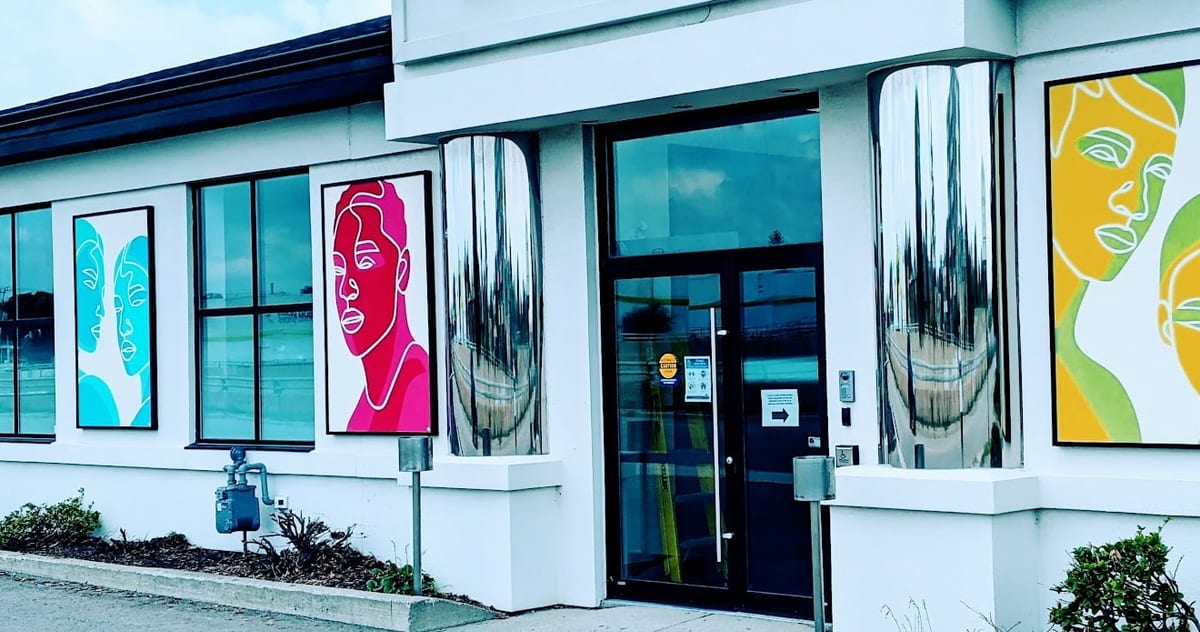The front entrance of the Deutschmann de Koning Law office on Kingsway Drive, with painted mural panels between its windows.